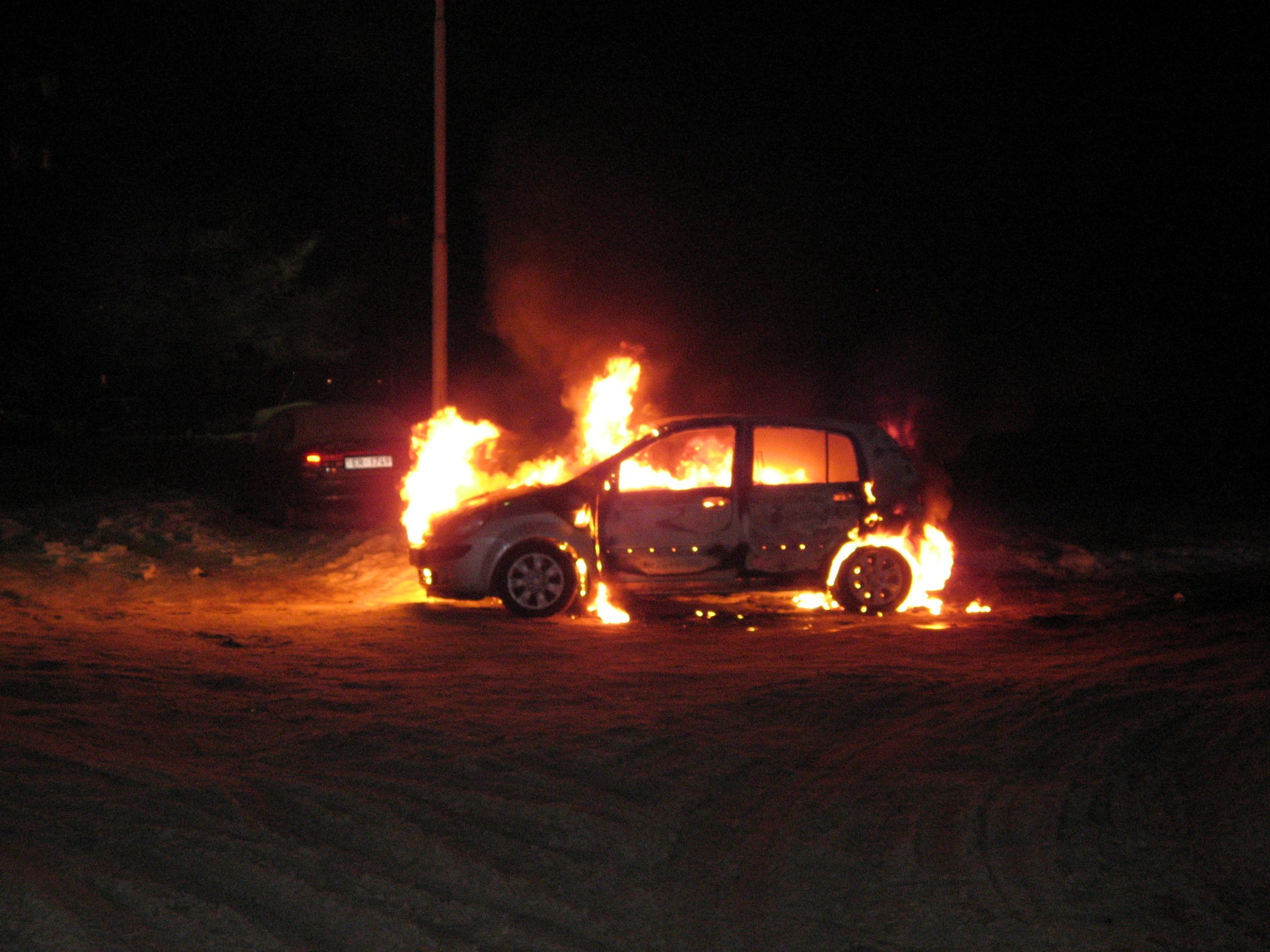 Degoša automašīna naktī, liesmas pārņēmušas salonu un motora daļu