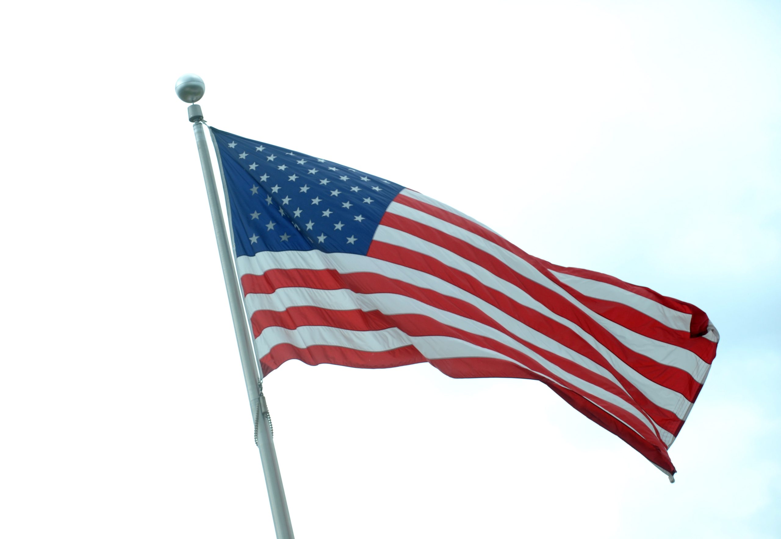 Amerikas Savienoto Valstu karogs plīvo vējā uz debesu fona.