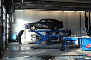 Automobilis uz pacēlāja tehniskās apskates stacijā.