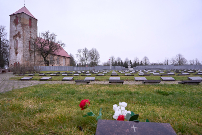 Lestenes baznīca un Brāļu kapu memoriāls ar ziediem priekšplānā