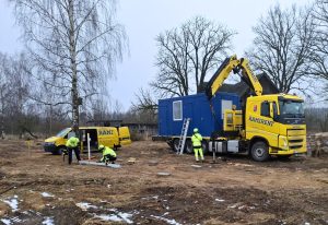 Ramirent kravas auto ar celtni, kas piegādā zilu moduļa konteineru būvlaukumā