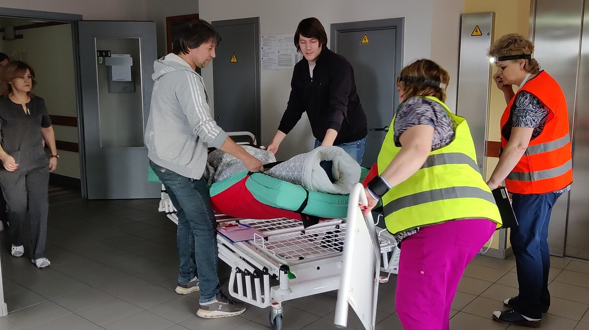 Medicīnas personāls un darbinieki Ventspils slimnīcā evakuācijas mācību laikā pārvieto pacientu uz nestuvēm.