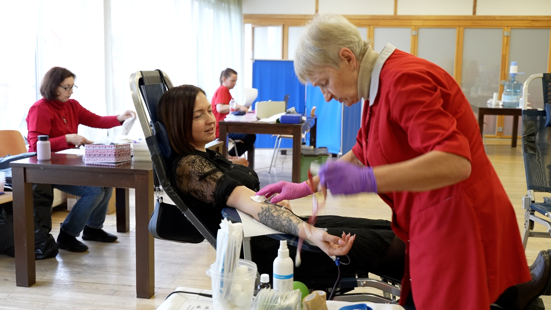 Sieviete ziedo asinis donoru centrā, medicīnas darbiniece veic procedūru.
