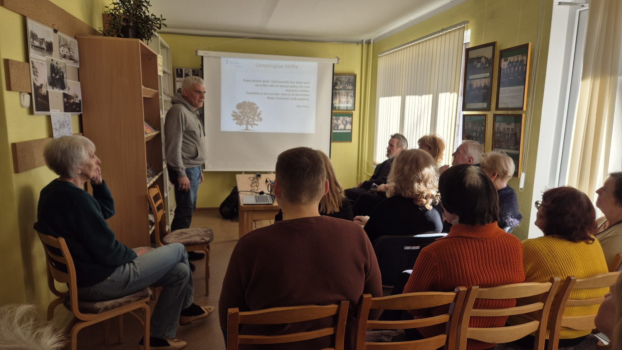 Cilvēku grupa lekcijā par ģenealoģiju bibliotēkā