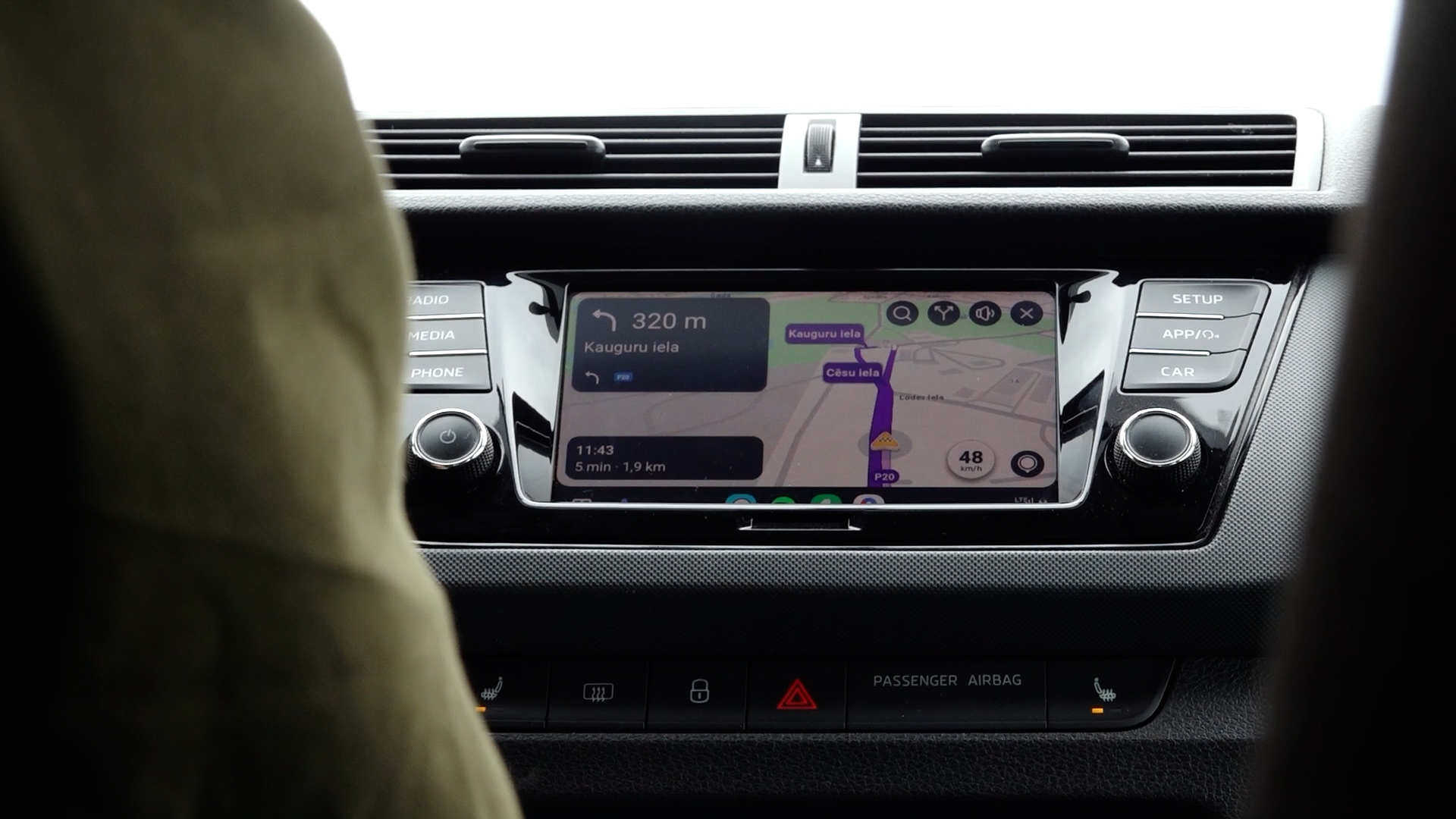 Navigācijas sistēma automašīnas centrālajā ekrānā ar maršrutu uz Kauguru ielu