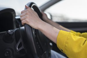 Sievietes rokas uz automašīnas stūres