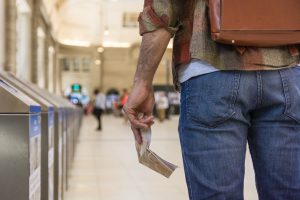 Ceļotājs ar mugursomu un karti rokā stāv sabiedriskā transporta stacijā