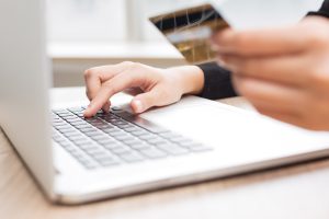 Persona veic tiešsaistes maksājumu, izmantojot kredītkarti un klēpjdatoru