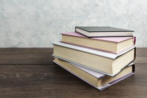 Grāmatu kaudze uz koka galda ar gaiši zilu fonu