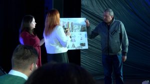Hakatona dalībnieki prezentē projektu uz skatuves