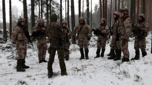Latvijas karavīri ziemas apstākļos apmācību laikā mežā.