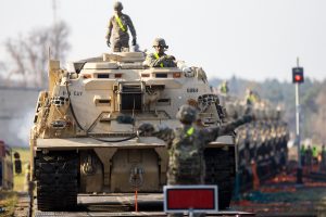 Bruņutransportieri uz dzelzceļa platformām, ko vada karavīri, gatavojoties militārai pārvietošanai