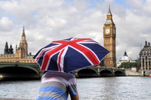 Cilvēks ar Lielbritānijas karoga lietussargu pie Temzas Londonā