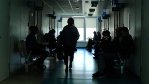 Cilvēki gaida rindā pie ārstiem poliklīnikas gaitenī