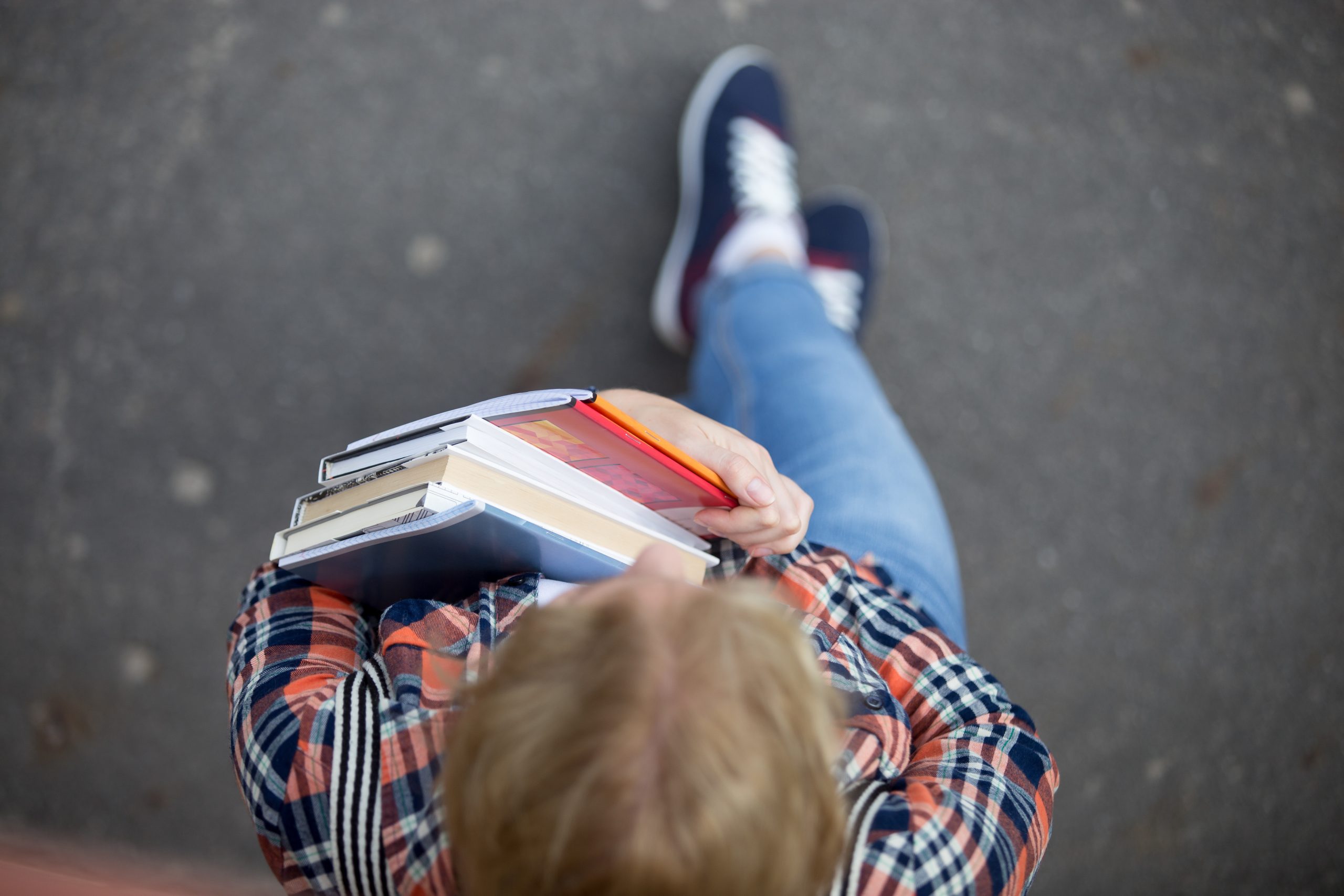 Skolēns ar grāmatām rokās skatās uz priekšu, redzams no augšas