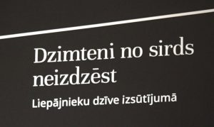 Uz melna fona rakstīts teksts "Dzimteni no sirds neizdzēst. Liepājnieku dzīve izsūtījumā".