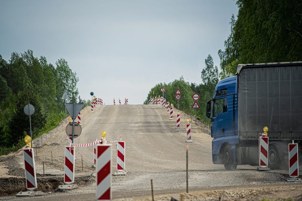 Ceļa būvniecības darbi ar smago automašīnu pie pagaidu grants seguma un ceļa zīmēm