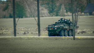 Militārs bruņutransportieris pārvietojas pa lauku ceļu militāro mācību laikā Latvijā