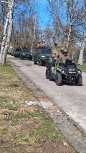 Latvijas karavīri militārajā formā brauc ar kvadriciklu un militārajiem transportlīdzekļiem kolonnā.