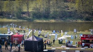 Brīvdabas pasākums pie upes ar ēdiena furgoniem un apmeklētājiem