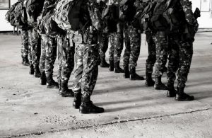 Militārie karavīri formastērpos stāv ierindā iekštelpās