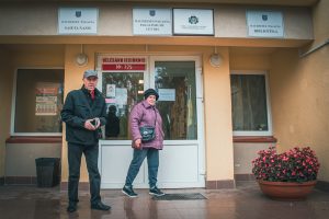 Divi cilvēki iznāk no vēlēšanu iecirkņa Daudzeses pagasta Saieta namā