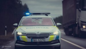 Latvijas policijas auto ar ieslēgtiem sirēnas signāliem uz ceļa.