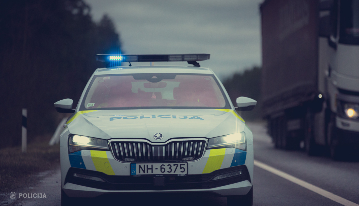 Latvijas policijas auto ar ieslēgtiem sirēnas signāliem uz ceļa.