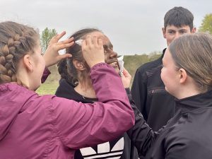Jaunieši pēc mācībām attīra seju no maskēšanās krāsas un smaida