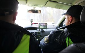 Policisti veic ātruma kontroli no dienesta automašīnas.