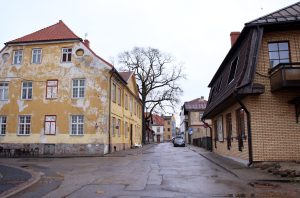 Vēsturiskas ēkas Cēsu vecpilsētā ar nolupušu fasādi.