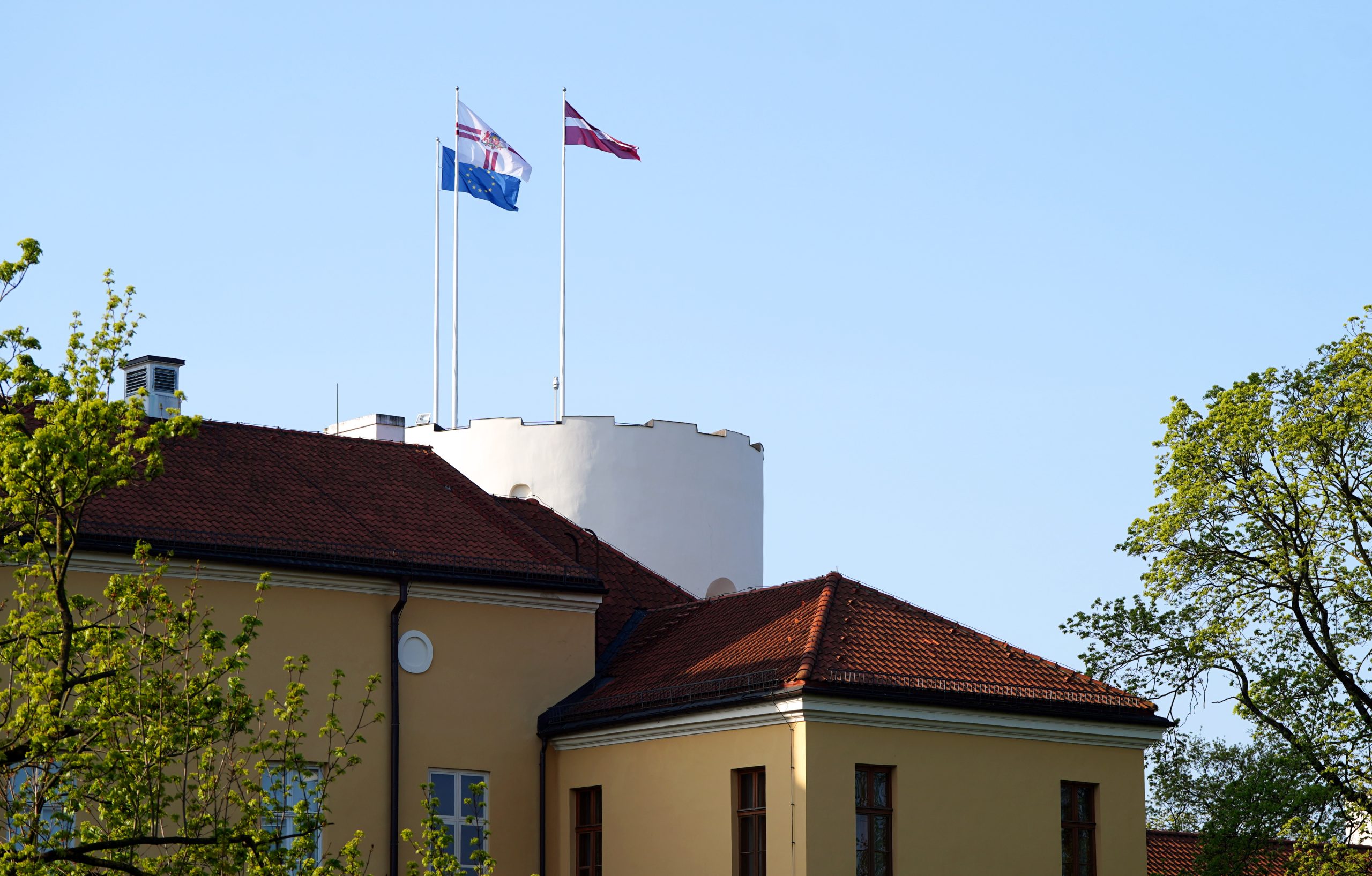 Rīgas pils tornis ar plīvojošiem Latvijas, ES un Valsts prezidenta karogiem