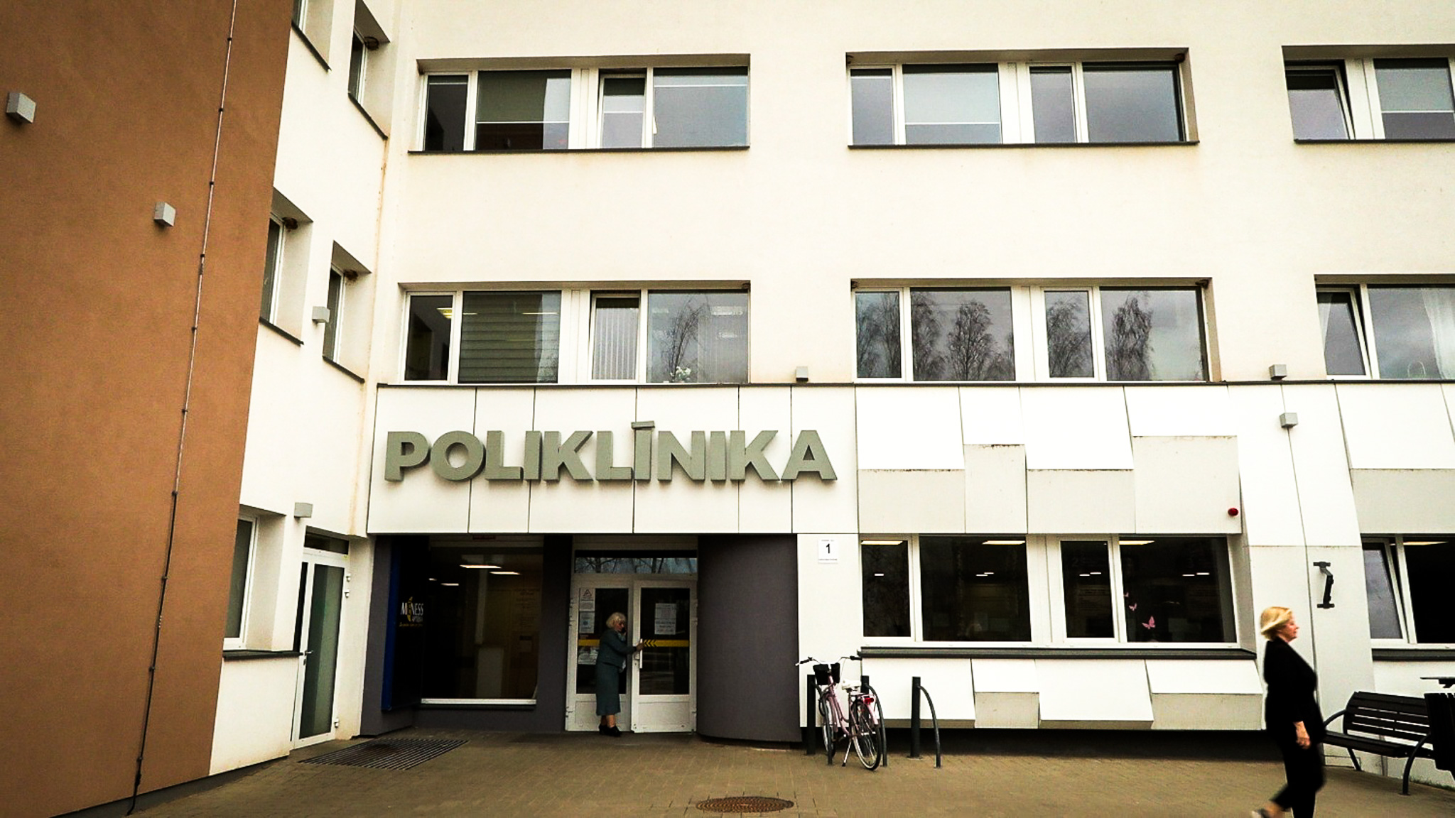 Mūsdienīga poliklīnikas ēka ar ieeju un uzrakstu Poliklīnika