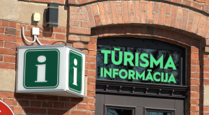 Tūrisma informācijas centra izkārtne uz ķieģeļu ēkas fasādes.