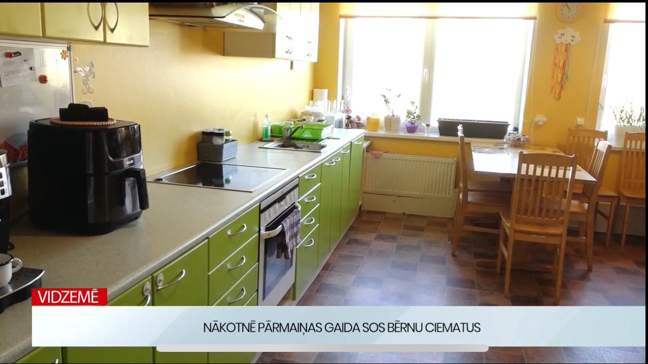 SOS bērnu ciemata virtuve ar zaļiem skapīšiem un ēdamzonu