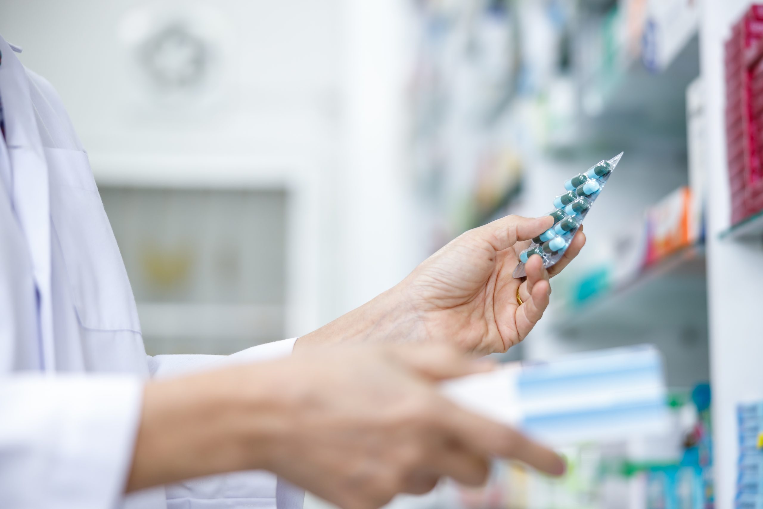 Farmaceite tur rokās zāļu iepakojumu aptiekā