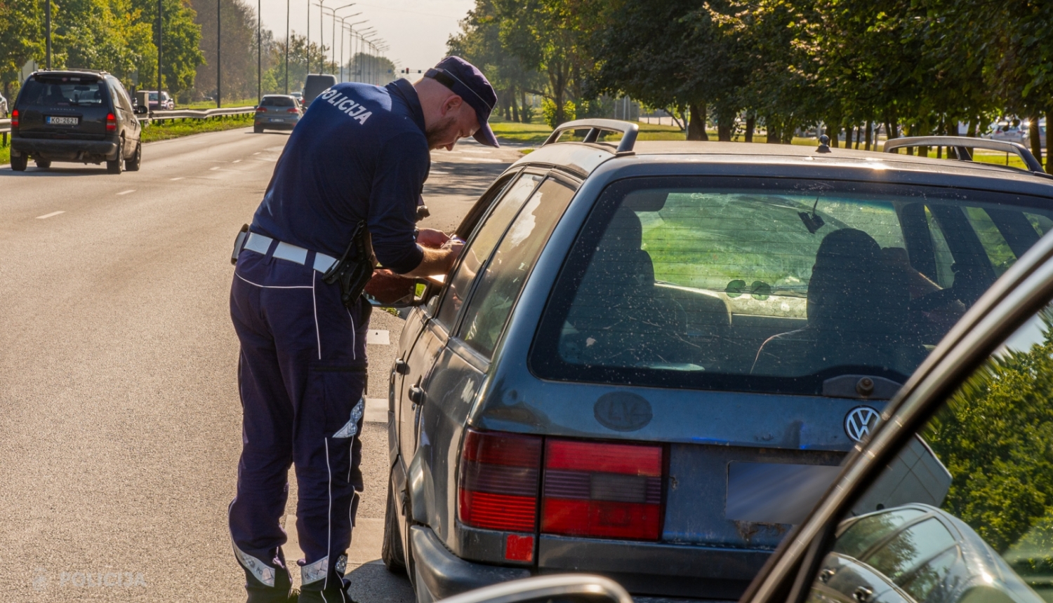 Latvijas policists formā pārbauda dokumentus pie automašīnas