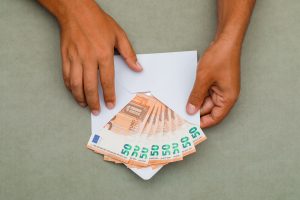 Aploksne ar 50 eiro banknotēm vīrieša rokās