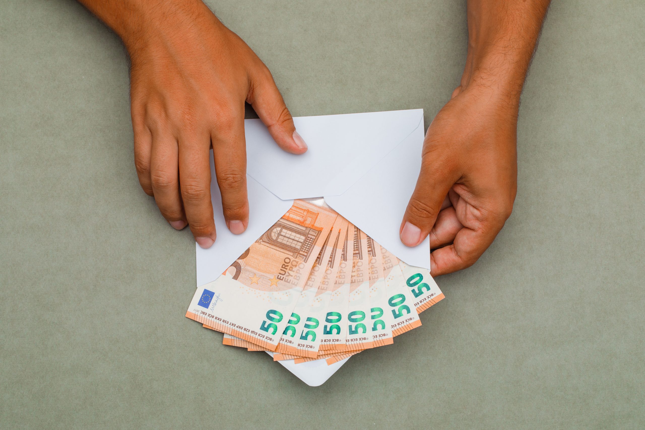 Aploksne ar 50 eiro banknotēm vīrieša rokās