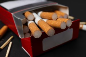 Atvērta cigarešu paciņa ar cigaretēm un sērkociņiem uz melna fona