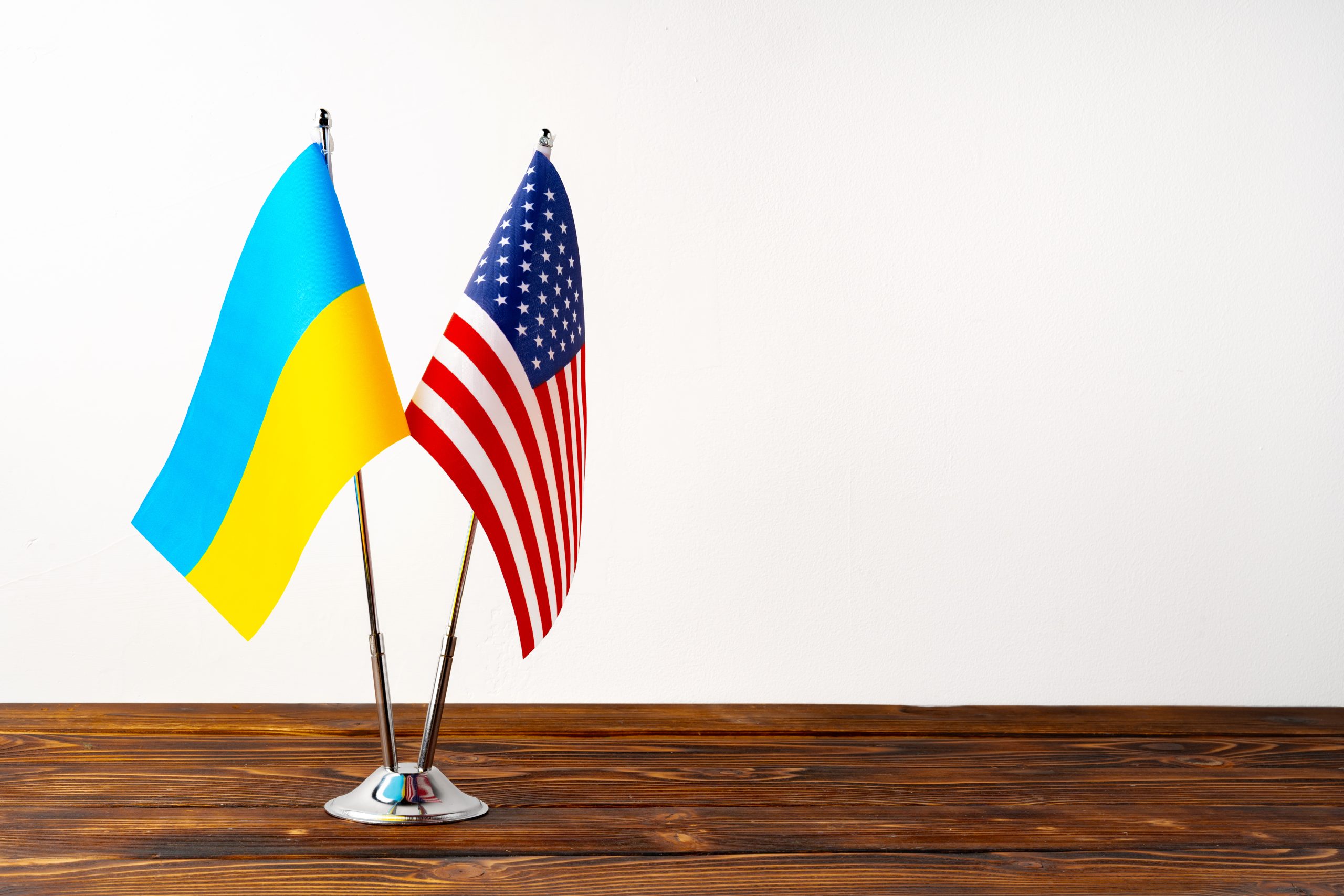 ASV un Ukrainas karogi uz galda koka pamatnes ar baltu fonu