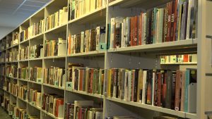Grāmatu plaukti bibliotēkā ar sakārtotiem izdevumiem alfabēta secībā