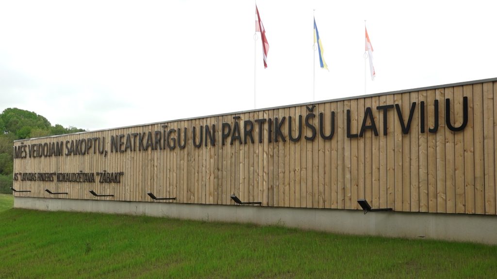 Koka apšuvuma siena ar uzrakstu "MĒS VEIDOJAM SAKOPTU, NEATKARĪGU UN PĀRTIKUŠU LATVIJU"