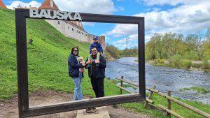 Jankovsku ģimene pie Bauskas pils rāmja ar upi fonā.