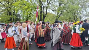 Tautastērpu gājiena dalībnieki Rīgā 4. maijā ar Latvijas karogu un ziediem