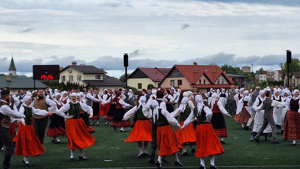 Latviešu tautas dejotāji tradicionālos tērpos koncertā uz stadionā