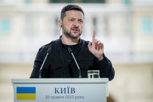 Ukrainas prezidents Volodimirs Zelenskis runā pie tribīnes ar Ukrainas karogu un uzrakstu “Kijiv, 10 травня 2025 року”
