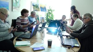 Seniori mācās izmantot viedtālruņus un datorus digitālo prasmju nodarbībā bibliotēkā