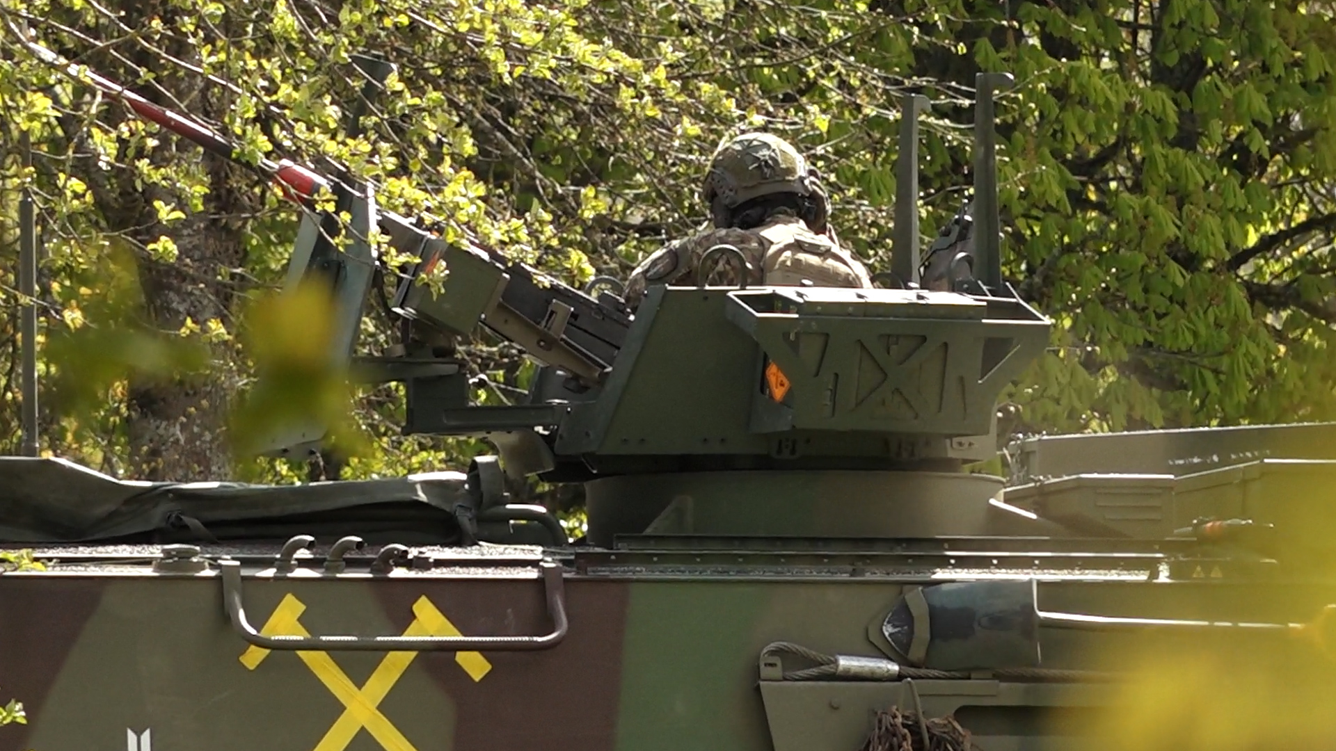 Karavīrs militārā transportlīdzekļa tornī ar ložmetēju mācību laikā