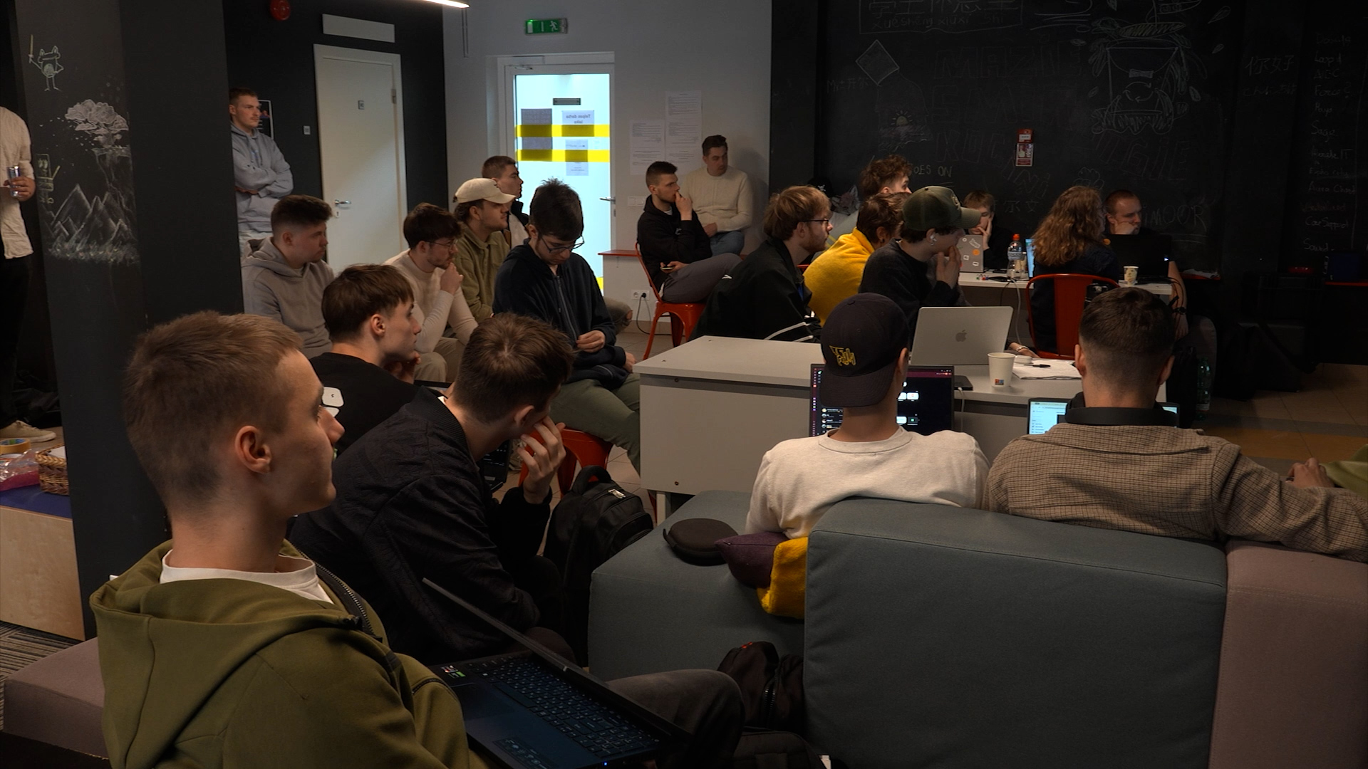Grupa studentu klausās prezentāciju vai lekciju telpā ar projekcijas ekrānu Ventspilī